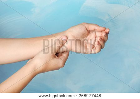 Woman Checking Pulse On Wrist Against Color Background, Closeup