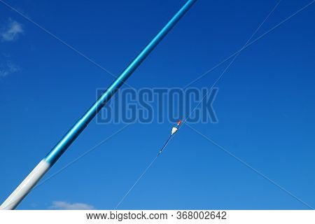 Ffishing Rod And Bobber Against Blue Sky Close-up