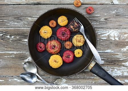 Gladiolus Bulbs On A Dark Frying Pan On A Gray Background. View From Above. Close Up