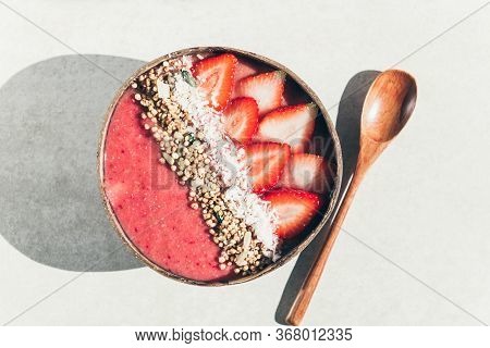 Pink Smoothie From Banana And Strawberries With Pieces Of Strawberries, Granola And Coconut Shreds O