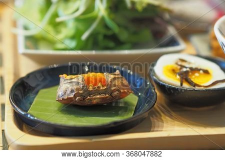 Crab Eggs In Crab Shell On Banana Leaf With Half Boiled Egg On A Table - Breakfast Set Japanese Styl