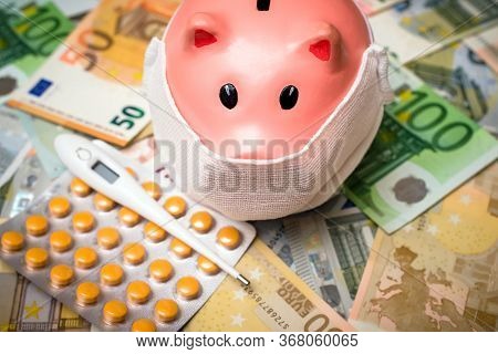 Piggy Bank In A Mask On A Background Of European Currency.the Concept Of Coronavrius Epidemic