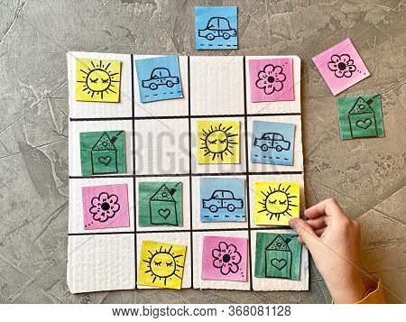 A Childs Hand Plays A Logical Game Of Sudoku, Rearranging Bright Cards.