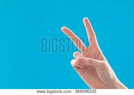 Close-up Of A Female Hand With Two Fingers Up A Symbol Of Peace Or Victory. Sign For The Letter V In