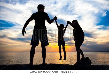 Happy Family Silhouette On The Sunset Background