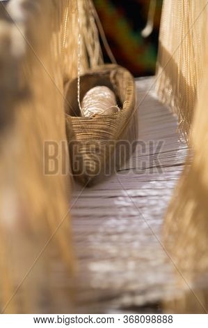The Loom's Shuttle Lies On The Tight Warp Threads Between The Heddles Vertical Photo