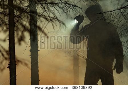 Rescue Search. Men Wearing Camouflage Clothing With Powerful Flashlight Between Trees And Fire Smoke