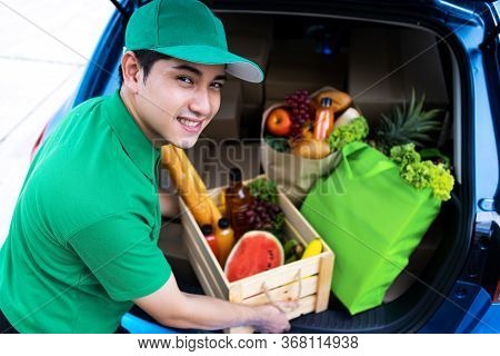 Asian Delivery Man In Green T-shirt Delivering Food, Fruit, Joice And Vegetable To Home - Online Gro