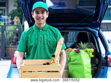 Asian Delivery Man In Green T-shirt Delivering Food, Fruit, Joice And Vegetable To Home - Online Gro