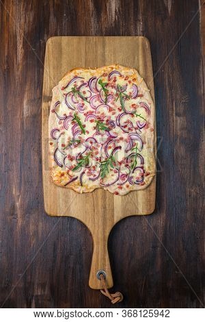 Traditional French dish tarte flambee cream cheese, bacon and onions. Flammkuchen from Alsace region. Flame cake.