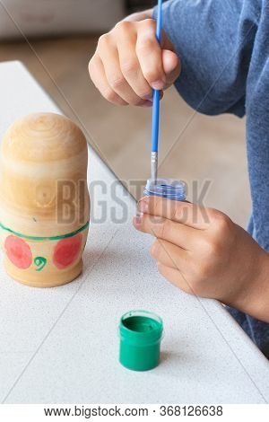 A Child Paints A Wooden Blank Of A Nesting Doll. Children's Crafts