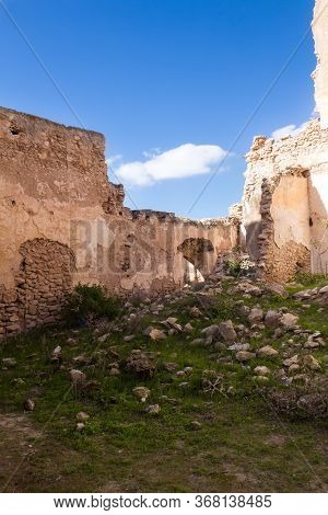 Walls Without A Facade In The Ruins Of Abandoned House. Yard With A Green Grass And Many Stones From