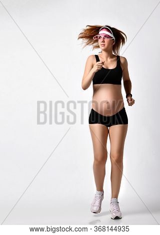 Pregnant Girl With Belly, In Green Sun Visor, Black Sport Shorts And Top, Pink Sneakers. She Is Jogg