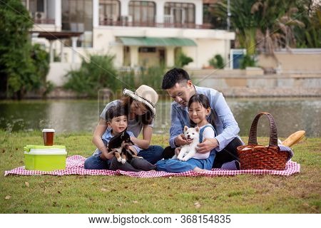 Asian Family Father Mother And Kids Pinic Together With Shiba Inu Dog On Field Near Pond