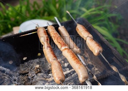 Close Up Of Toasted Sausages On Skewers. Succulent Kupaty Roasting On Chargrill. Concept Of Picnic O