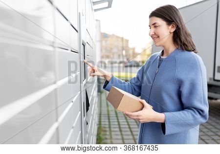 mail delivery and post service concept - happy smiling woman with box at outdoor automated parcel machine choosing operation on touch screen