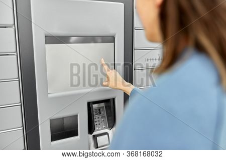 mail delivery and post service concept - close up of woman choosing operation on outdoor automated parcel machine's touch screen
