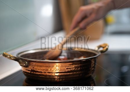 Vintage Textured Copper Cooking Pot On Kithcen With Male Hand Cooking Mixing Food In Pot