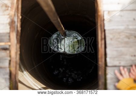 Blue Bucked Inside Water Well. A Water Well With An Old Iron Bucket