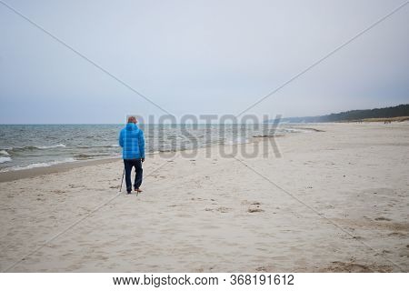 Debki, Poland- May 25, 2020: A Lonely Man Trains Nordic Walking On The Beach Of The Baltic Sea