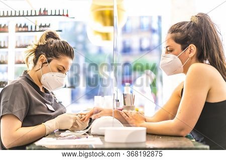 Manicure And Pedicure Beauty Salon With Security Measures And People With Masks, Performing A Pedicu