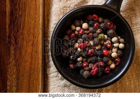 Mix Of Peppercorns In Black Bowl On Linen Cloth Closeup Near Wooden Board Top View Layflat