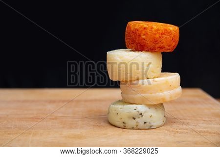 Whole Cheese Blocks Stacked On Wooden Table Against Dark Wall Background. Closeup, Side View, Copy S