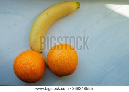 Concept Of Male Potency. Banana And Two Orange Fruits Isolated On A White Background.