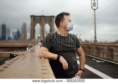Man Wearing Protection Face Mask On Famous Brooklyn Bridge In Rainy Summer Day. Landmarks Of New Yor