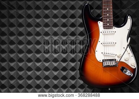 Sunburst Electric Guitar Standing Over Acoustic Foam Panel Background