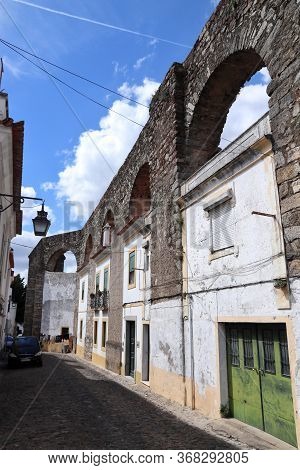 Evora Town In Portugal. Unesco World Heritage Site. Prata Aqueduct With Homes Beneath Arches.