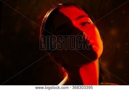 Portrait of a beautiful girl with shiny make-up and red arrows on her eyes in red light. Make-up and cosmetics concept. Beauty, fashion.