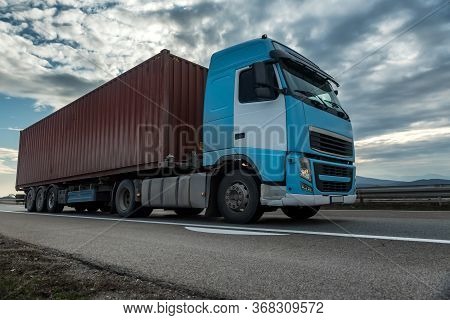 Blue Semi Trailer Truck On A Highway Driving At Bright Sunny Sunset. Transportation Vehicle Close Up