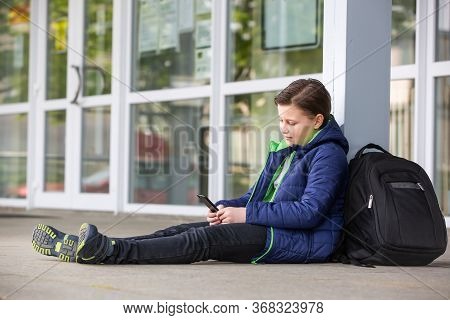 Truancy Concept, Young Boy Staying Away From The School And Playing Games On The Mobile, Absence Fro