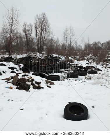 Old Used Tire Covers And Other Garbage In The Snow On The Landfill In Winter. Environmental Pollutio