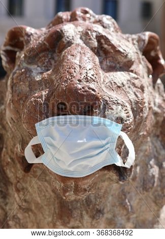 Funny Statue Of Red Lion In Venice In Italy In Surgical Mask During Lockdown By Corona Virus