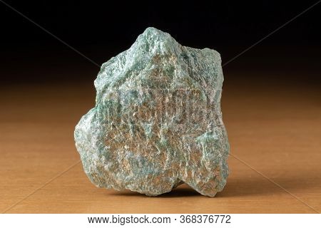 Rock Of Fuchsite Mineral From Brazil Over A Wooden Table