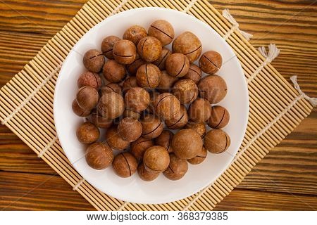 Delicious Macadamia Nuts On  Plate On  Wooden Background