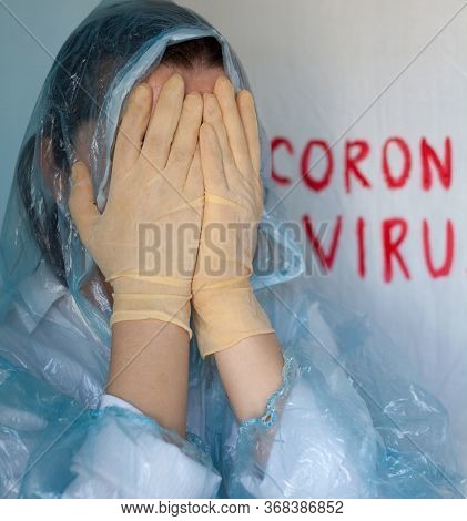 Woman In A Protective Suit Closing Her Face. Inscription Coronavirus In The Background. Coronavirus 