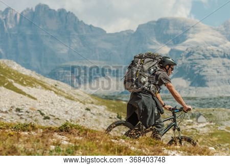Caucasian Biker In His 30s Wearing Large Backpack Riding On The Mountain Trail In Italian Dolomites 