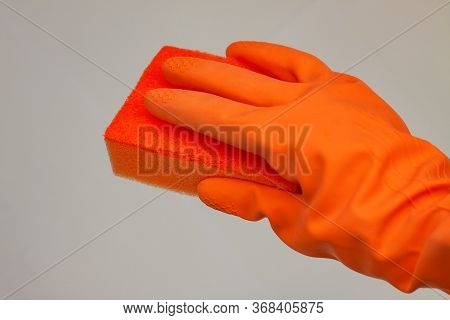 Orange Glove For Cleaning With An Orange Wisp On A Grey Background With A Copy Space