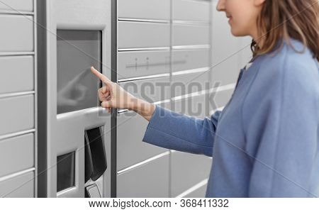 mail delivery and post service concept - close up of happy smiling woman choosing operation on outdoor automated parcel machine's touch screen