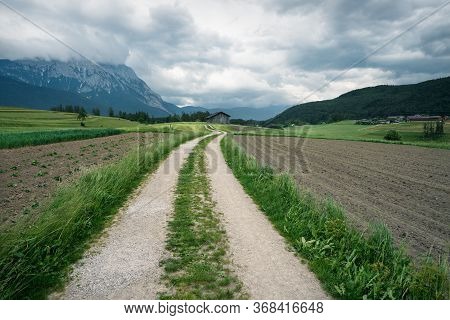 Winding Path Through Farmland With Austrian Alps And Stormy Weather, Mieminger Plateau, Tyrol, Austr