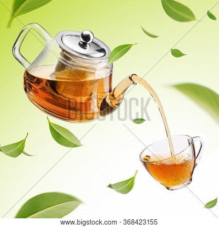 Jug Pouring Hot Tea Into Glass Cup With Flying Whirl Green Tea Leaves In The Air, Healthy Products B