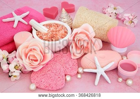 Beauty treatment for skin care for rejuvenation with ex foliation Himalayan mineral salts, cleansing products & apple blossom flowers on pink background. Anti ageing treatment health care concept.