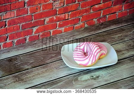 Two Fresh Donuts In Pink Glaze On A White Ceramic Plate.