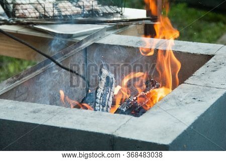 Firewood Burning In The Grill. Fire Flames. B-b-q Meat At The Background. Close Up.