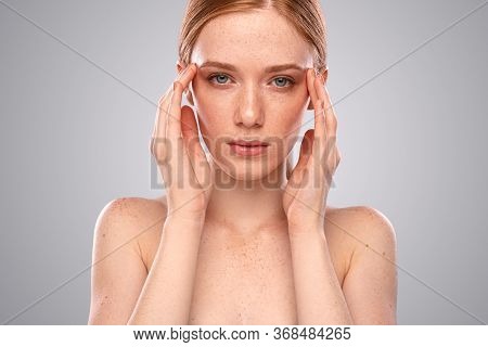 Beautiful Young Female With Freckled Skin Touching Temples And Looking At Camera While Suffering Fro