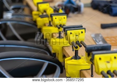 Many Yellow Vises Are Set On The Work Bench At The School. New Grips Or Jaw Vices Fixed At Woodwork 