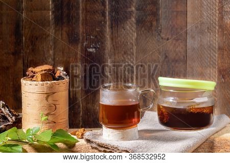 Healing Beverage From Birch Mushroom Chaga, Mushroom Pieces, Twig On Wooden Plank On Old Wooden Back
